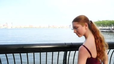 New Jersey rıhtımı boyunca dans eden genç, güzel balerin New York silueti arka planda.