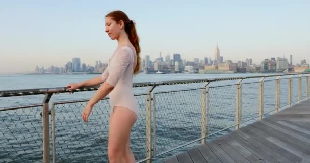 ニューヨークのスカイラインを背景に ニュージャージーのウォーターフロントに沿って踊る若い美しいバレリーナ — ストック動画
