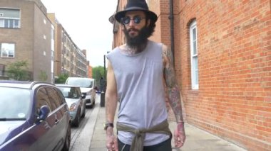 Shoreditch ilçesindeki tuğla bir duvarda genç dövmeli bir adam görüntüsü. Londra, İngiltere. Hipster tarzı