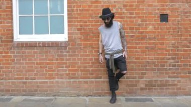 Shoreditch ilçesindeki tuğla bir duvarda genç dövmeli bir adam görüntüsü. Londra, İngiltere. Hipster tarzı