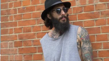 Shoreditch ilçesindeki tuğla bir duvarda genç dövmeli bir adam görüntüsü. Londra, İngiltere. Hipster tarzı