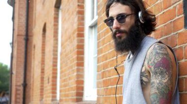 Shoreditch ilçesindeki tuğla bir duvarda genç dövmeli bir adam görüntüsü. Londra, İngiltere. Hipster tarzı