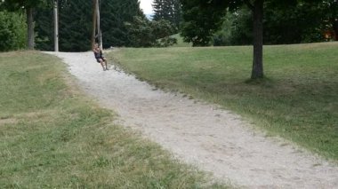 Açık havada halatla çizilmiş mutlu bir çocuk. Lavarone 'daki Palu Parkı. Burası, İtalya 'nın Trentino Alto Adige bölgesindeki gölüyle ünlüdür..
