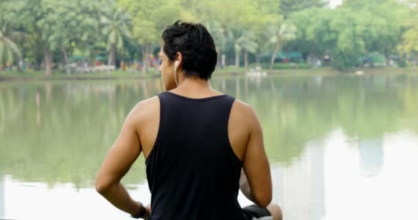 Jeune Homme Assis Bord Lac Avec Smartphone Écouteurs — Video
