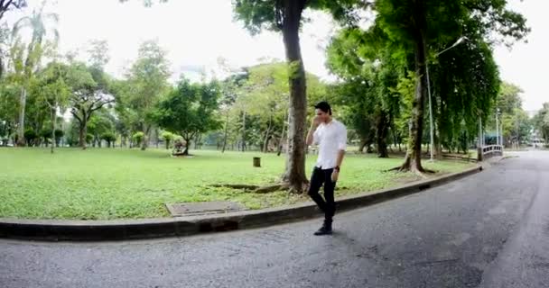 Νεαρός Άνδρας Περπατά Στο Πάρκο Και Καλεί Στο Τηλέφωνο — Αρχείο Βίντεο