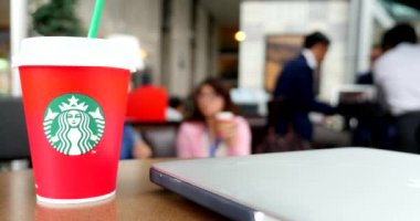 masada dizüstü bilgisayar ve arka planda insanlar ile starbucks kahve tek kullanımlık kırmızı fincan