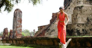 Genç kadın Ayutthaya, Tayland 'da geleneksel tapınağın önünde dans ediyor.