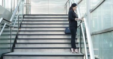 Young businesswoman with the laptop working on stairs