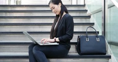 Young businesswoman with the laptop working on stairs