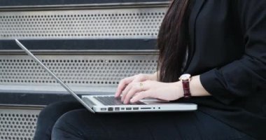 Young businesswoman with the laptop working on stairs
