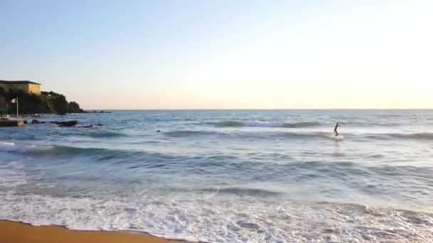 夕日の光の中でビーチで波に乗るサーファー — ストック動画