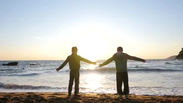 夕阳西下时，年轻的兄弟们在海面上的西罗埃特画像. — 图库视频影像