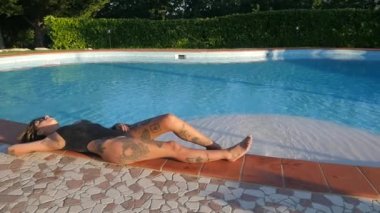 Seksi dövmeli kadın portre yüzme havuzu tesisi tarafından güneşlenme.
