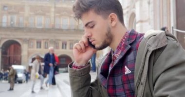 Kendinden emin genç adam sokakta telefonda konuşuyor