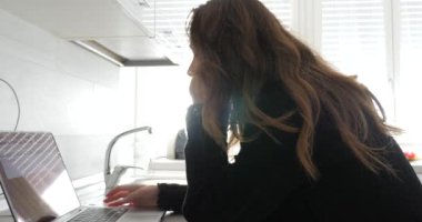 Evde dizüstü bilgisayarda çalışan bir kadın.