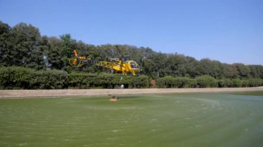 nehir suyu üzerinde uçan sarı helikopter