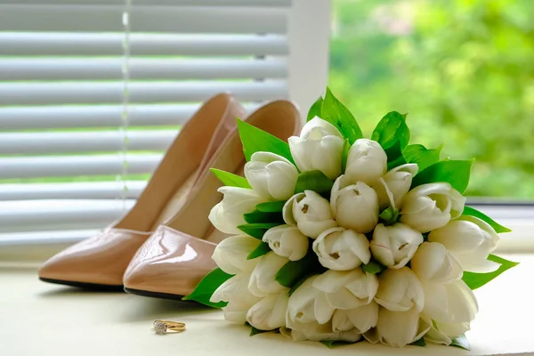 Bride`s wedding accessories: wedding shoes, rings and bouquet or boutonniere with tender flowers