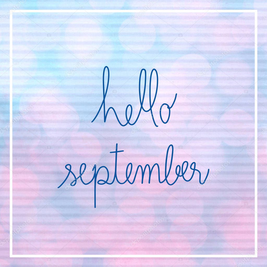 Hello September lettering with bokeh light on blue and pink corrugated paper.