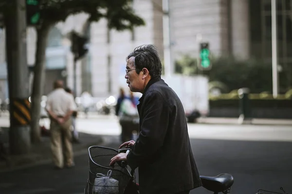 Alter Mann hält sein Fahrrad über die Straße — Stockfoto