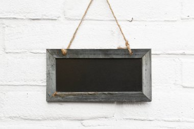 Beyaz tuğla zemin üzerine asılı kendi metin için yer ile boş yazı tahtası