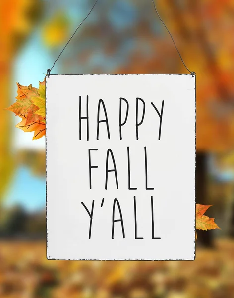 Happy fall you all autumn text on white plate board banner leaves blur background