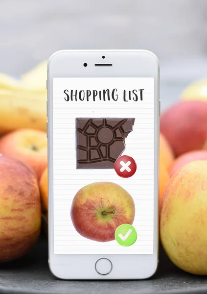 Phone with shopping list healthy vs unhealthy chocolat apple dieting