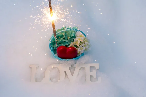 International women day.  March 8 and Valentine\'s day. Basket with flowers on a white snow background. Bengal fire with sparks and beautiful bokeh.