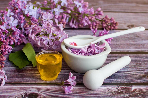 a jar of fragrant flower honey. Honey saved and lilac flowers. On black and wooden background.