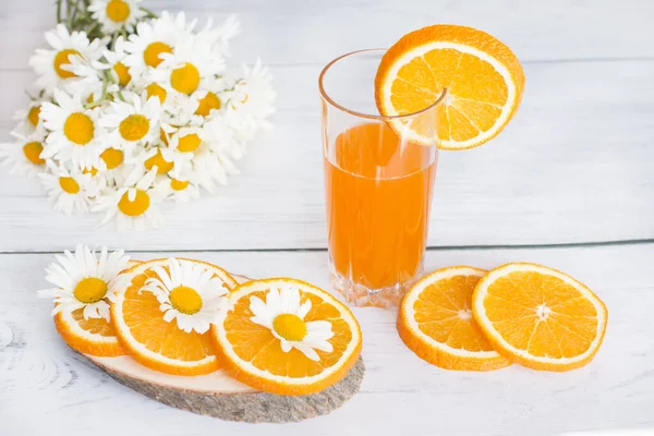 Orange vitamin drink. Decanter and glass with orange drink decorated with white daisies.