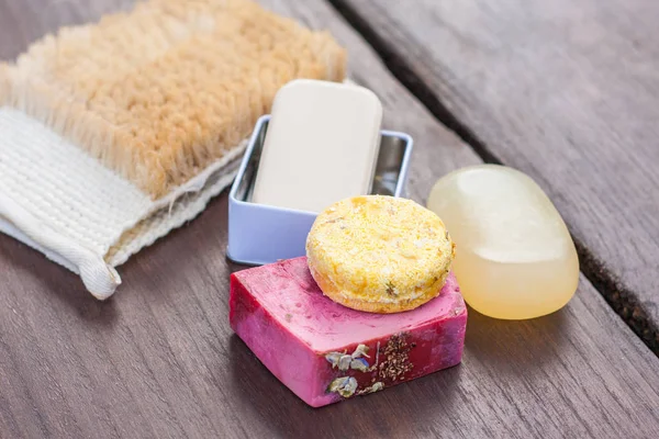 Yığılmış doğal sabun, duş jeli, banyo bomba ve şampuan çubukları koyu ahşap bir masa üzerinde bir renkli seçim. Sıfır için atık, plastik ücretsiz banyo ve ev.