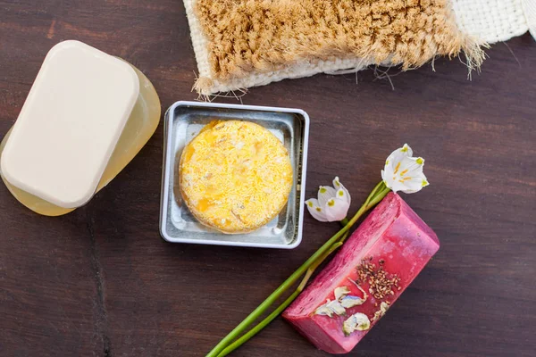 Yığılmış doğal sabun, duş jeli, banyo bomba ve şampuan çubukları koyu ahşap bir masa üzerinde bir renkli seçim. Sıfır için atık, plastik ücretsiz banyo ve ev.