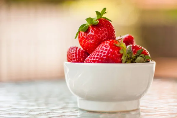 Taze ve tatlı olgun kırmızı çilek İspanya'dan bir masada koyu ahşap açık havada. Sağlıklı yiyecek ya da tatlı bir küçük beyaz seramik kase bir olarak hizmet.