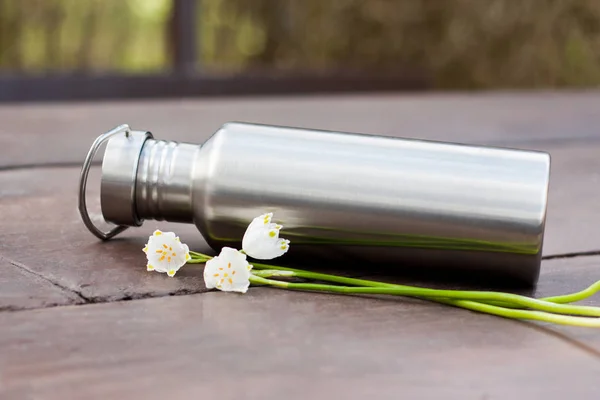 Sıfır atık yaşam tarzı - günlük öğeleri içine bir göz. Bir izole dayanıklı paslanmaz çelik su şişesi, bahar kar tanesi çiçek dekorasyon olarak.