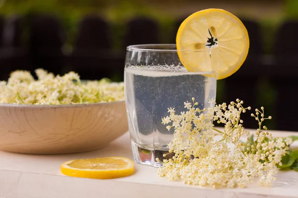 Freshly picked elderberry flowers in a beautiful ceramic bowl with lemon slices as decoration. The flowers of Sambucus species are used to produce elderflower cordial, homemade sweet syrup or juice.