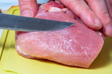 Keskin bir bıçakla taze et kesen bir adamın yakın çekimi. Domuz eti pişiriyorum. Et yemeği konsepti..