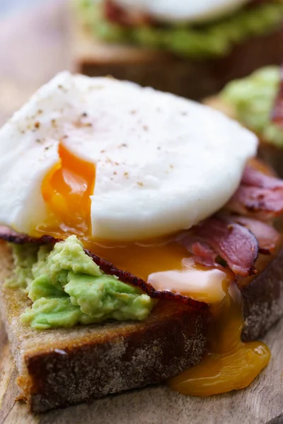 Poached egg toasts with avocado and bacon.