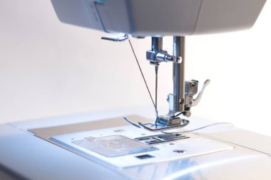 Dikiş makinesi. Kancaya yakın çekim ve ayaklar dikiş makinesinde.