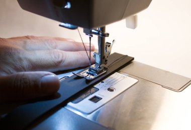 Dikiş makinesi. Kancaya yakın çekim ve ayaklar dikiş makinesinde.