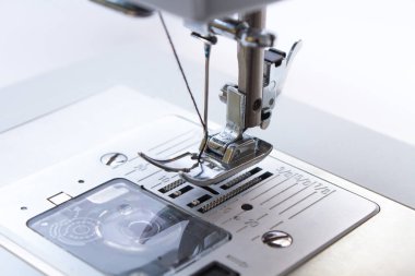 Dikiş makinesi. Kancaya yakın çekim ve ayaklar dikiş makinesinde.