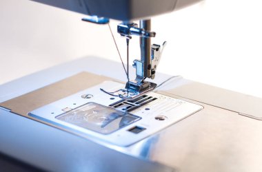 Dikiş makinesi. Kancaya yakın çekim ve ayaklar dikiş makinesinde.