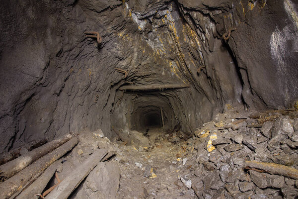 Underground abandoned iron ore mine tunnel with collapsed wooden timbering