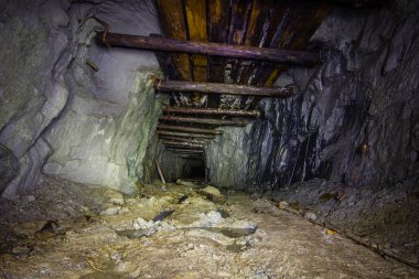 Old gold mine underground tunnel with collapsed wooden timbering