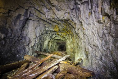 Old gold mine underground tunnel with collapsed wooden timbering