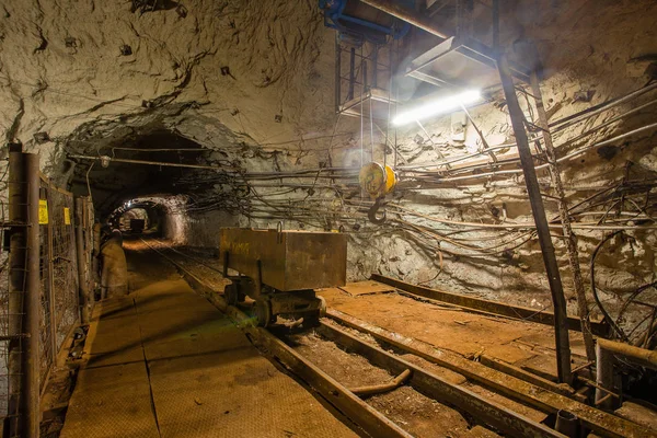 Underground gold mine shaft tunnel drift with rails and light mining cart wagon