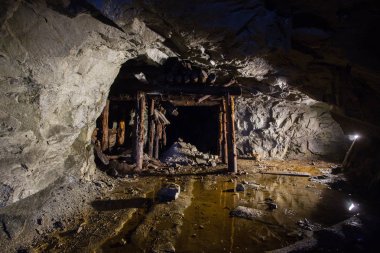 Old gold mine underground tunnel with collapsed wooden timbering