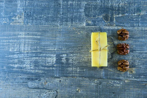 Sarı peynir, mavi ahşap bir masada ceviz kabuğu.