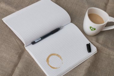 açık jel kalem ve masanın üzerinde keten backgruond üzerinde süt cofee fincan ile dizüstü bir fincan kahve rafineri