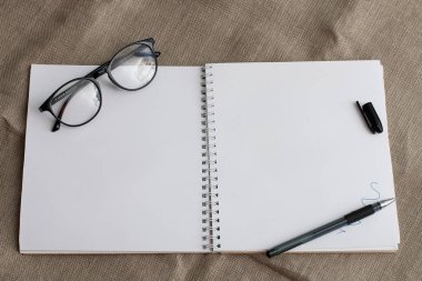 bu gözlük ve mavi jel kalem boya sayfada bir satır ile keten baxkground üzerinde temiz sayfaları ile dizüstü