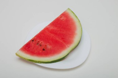 beyaz bir tabak üst görünüm beyaz arka plan kırmızı yeşil tohumlar siyah üzerinde karpuz dilim