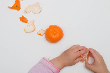 çocukların elleri beyaz bir arka plan pembe turuncu üzerinde dilimler halinde mandalina bölmek